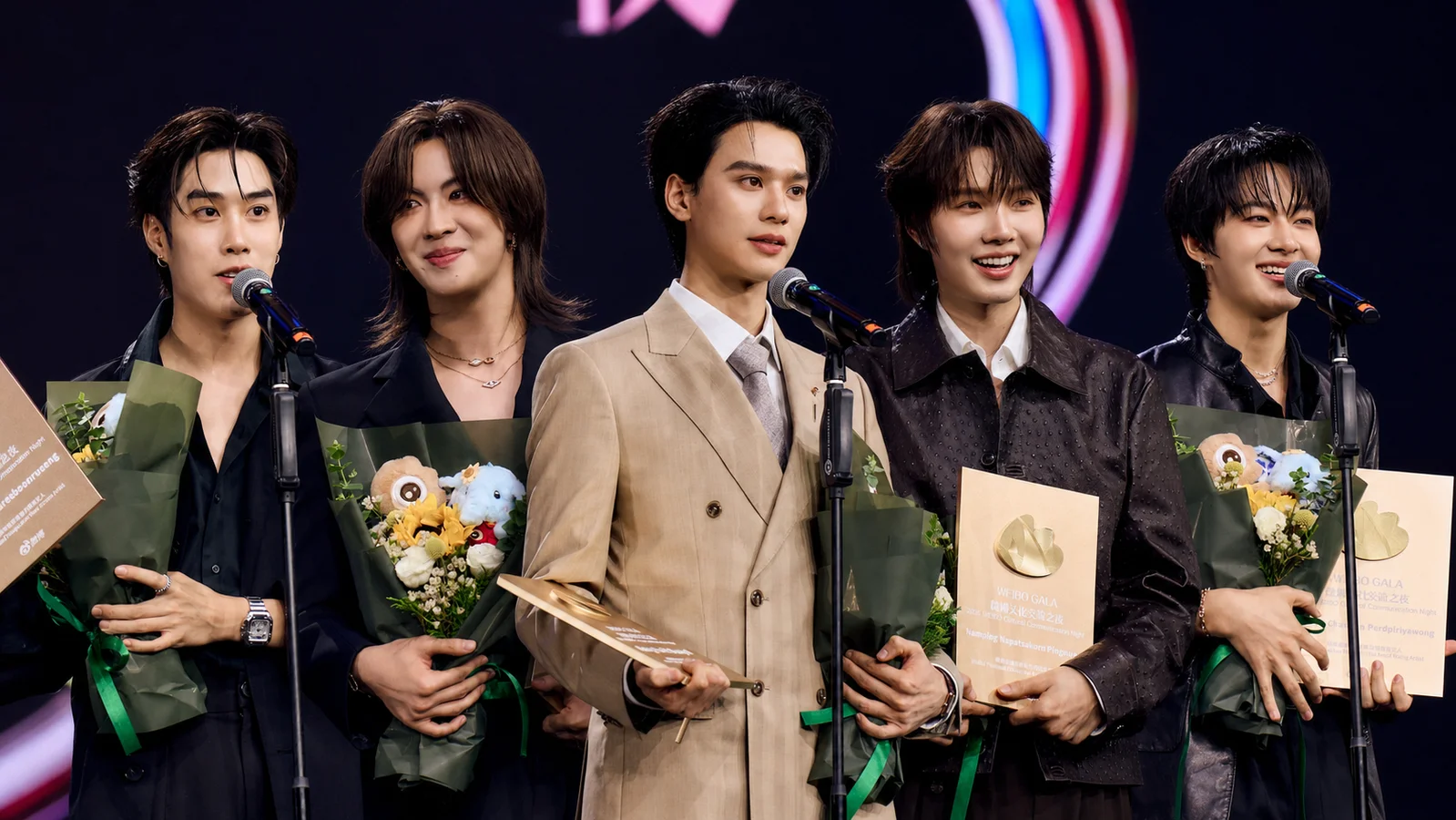 Composite image of Tle Matimun, FirstOne Wannakorn, Keng Harit, Namping Napatsakorn and NuNew Chawarin holding bouquets and award plaques at the 2026 Weibo Cultural Communication Night in Bangkok.