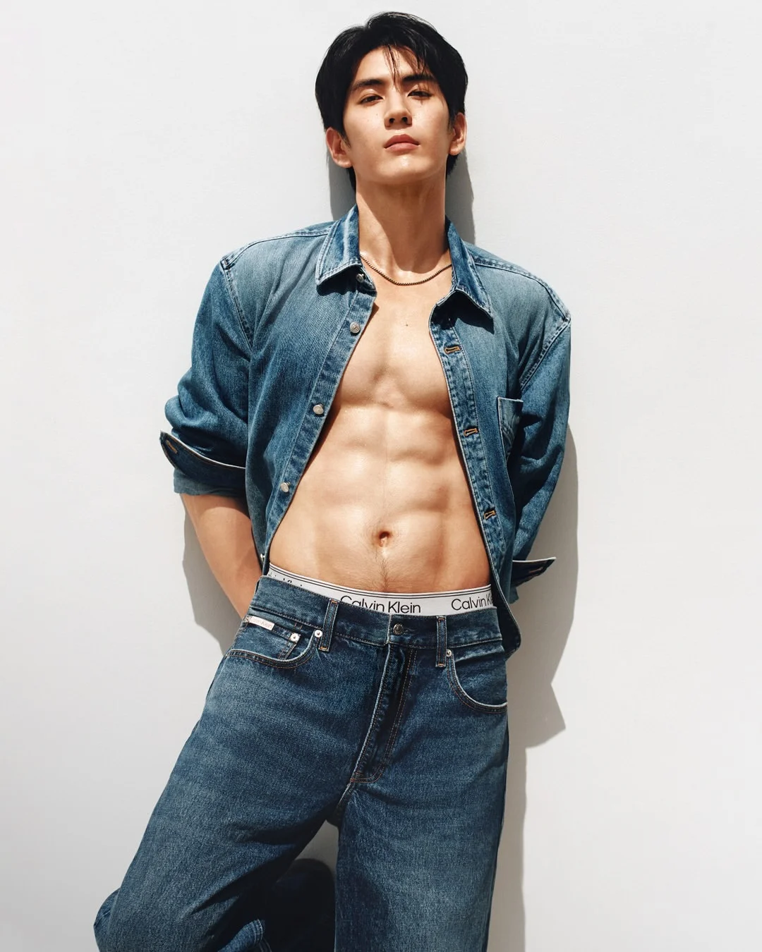Sea Tawinan poses in an open denim shirt and jeans, revealing the waistband of his Calvin Klein underwear.