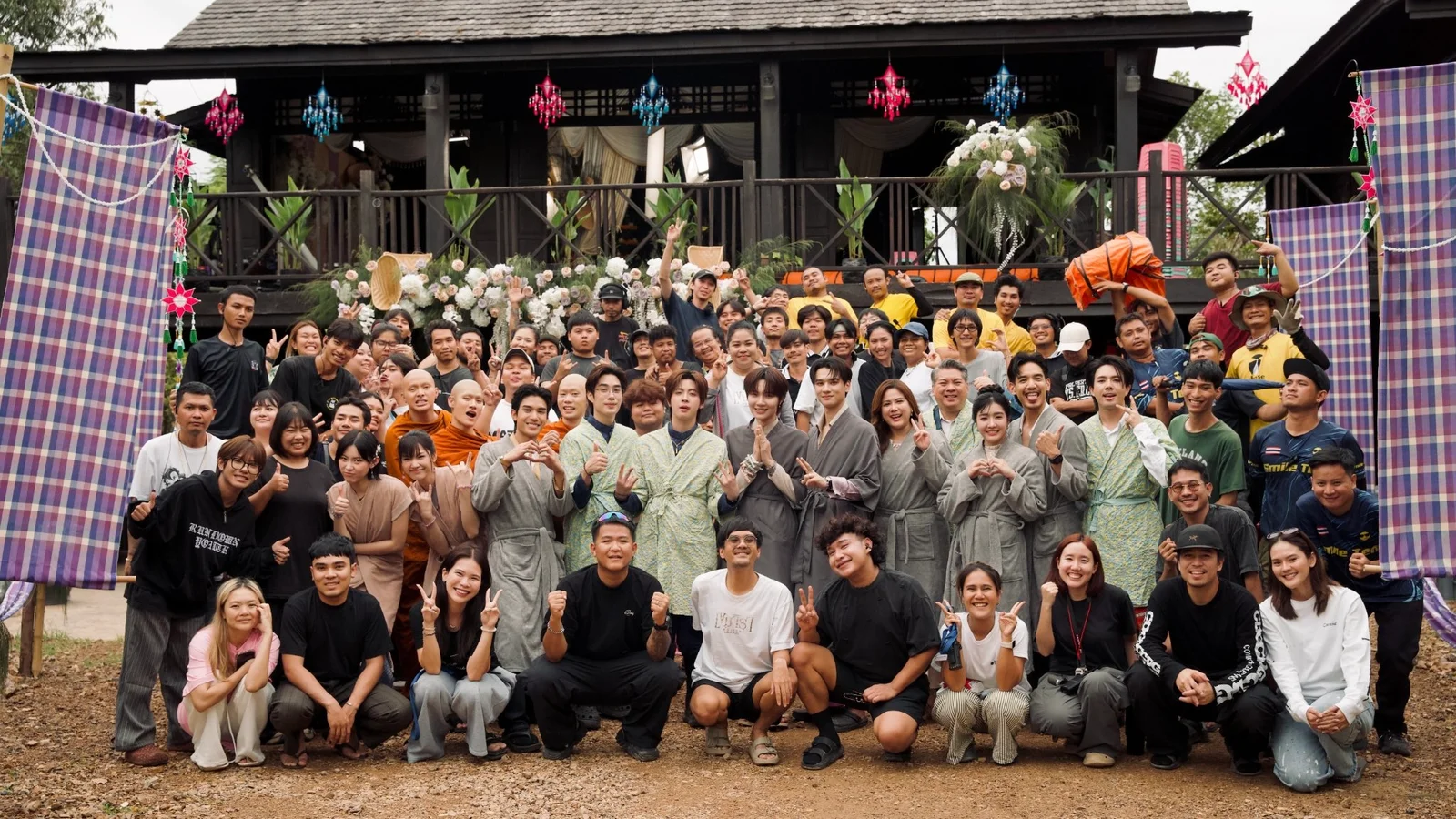 The cast and production crew of Khemjira Forever pose together outside the series’ decorated traditional wooden house set after completing filming.
